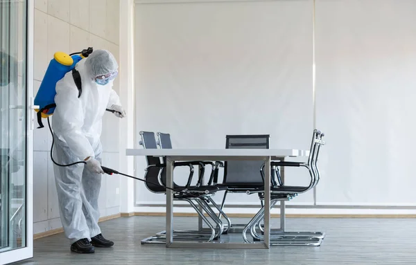 コロナウイルス流行中の会議室での清掃と消毒消毒作業のための専門チーム感染予防と流行の制御保護スーツとマスク ストック写真