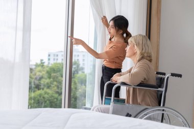 Anne tekerlekli sandalyede oturuyor ve evlatlık kızı yatak odasındaki renk beyazına şefkat ve içtenlikle bakıyor. Alışılmadık görünüş, çeşitlilik, kalıtım konsepti..