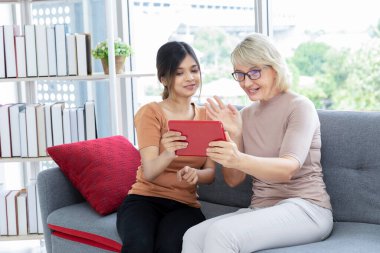 Kız ve anne videosu tabletle aranıyor ve evde oturma odasında birlikte oturuyorlar. Alışılmadık görünüş, çeşitlilik, kalıtım konsepti..