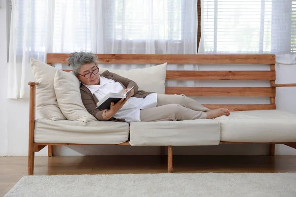老人ホームでソファの上で一人で本を読む ロイヤリティフリーのストック写真