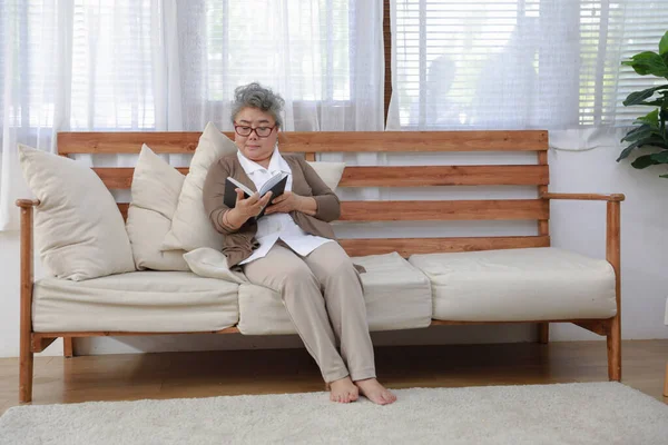老人ホームでソファの上で一人で本を読む ストック写真