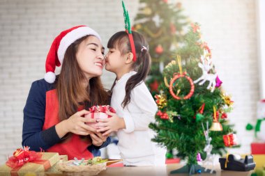 Mutlu anne ve kızın portresi Noel ağacını evin içinde süslüyor. Portre seven aile yakın plan. Büyük, güzel bir Noel ağacı arka planı..