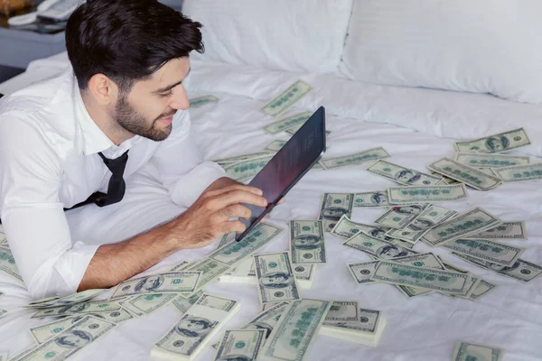 Tabletli Mutlu Genç Işadamı Etrafında Dolarla Yatakta Dinleniyor Başarı Servet — Stok fotoğraf