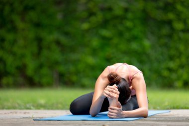 İnanılmaz güçlü genç Asya fitness kadını görüntüsü bahçede yoga esneme egzersizleri yapıyor..