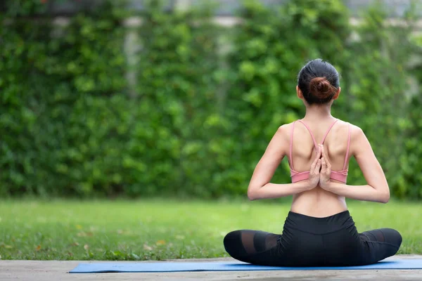 İnanılmaz güçlü genç Asya fitness kadını görüntüsü bahçede yoga esneme egzersizleri yapıyor..