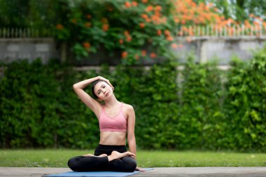 İnanılmaz güçlü genç Asya fitness kadını görüntüsü bahçede yoga esneme egzersizleri yapıyor..