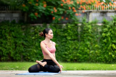 İnanılmaz güçlü genç Asya fitness kadını görüntüsü bahçede yoga esneme egzersizleri yapıyor..