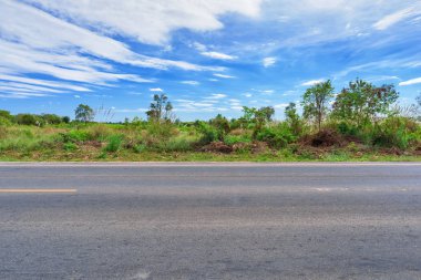 Asfalt yol kenarı manzarası ve kırsal alan.