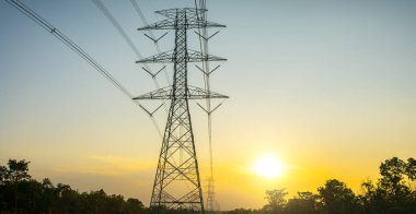 Günbatımı gökyüzü ile yüksek voltaj direği
