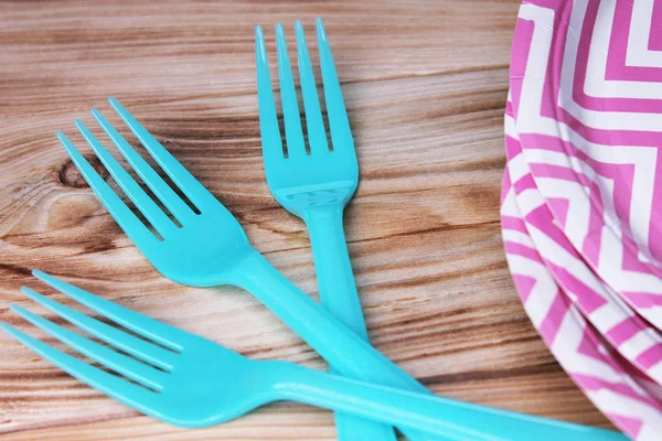 Plastic forks and paper plates in detail on wooden background