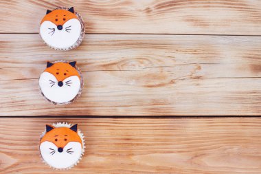 Ahşap arka plan üzerinde ayrıntılı badem yüzünden fox ile üç şekilde dekore edilmiş cupcakes yapıştırın