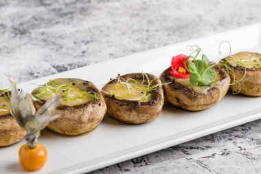 peynir beyaz plaka üzerinde ızgara mantar dolması