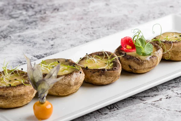 peynir beyaz plaka üzerinde ızgara mantar dolması