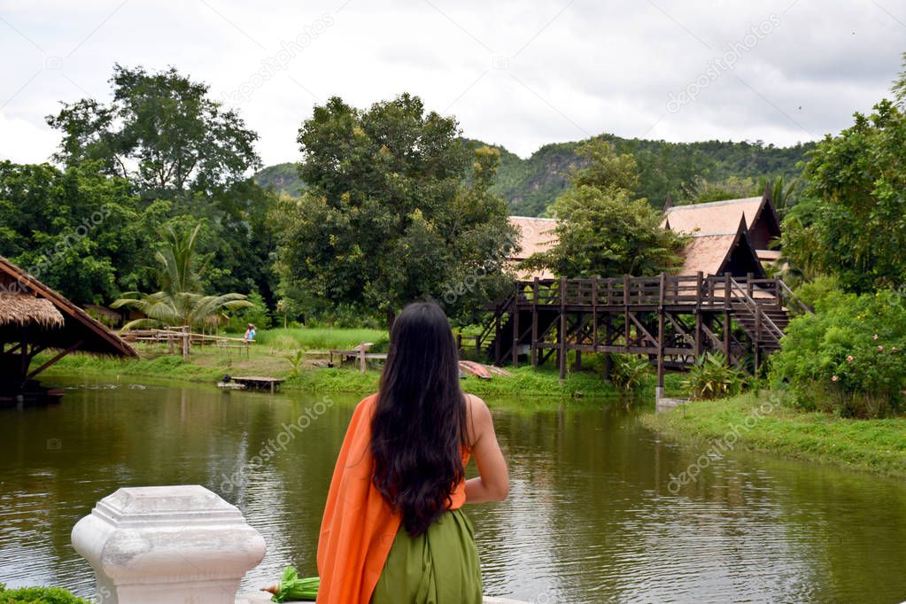 Kanchanaburi, Thailand, 09.09.2019: Beautiful Thai girl in traditional Thai, Siamese dress with green umbrella and accessories in 
