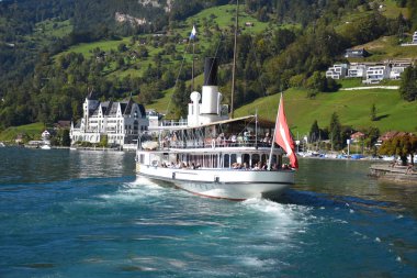Vitznau, İsviçre - 29 Eylül 2019: İsviçre bayrağı ve limandan ayrılan turistler