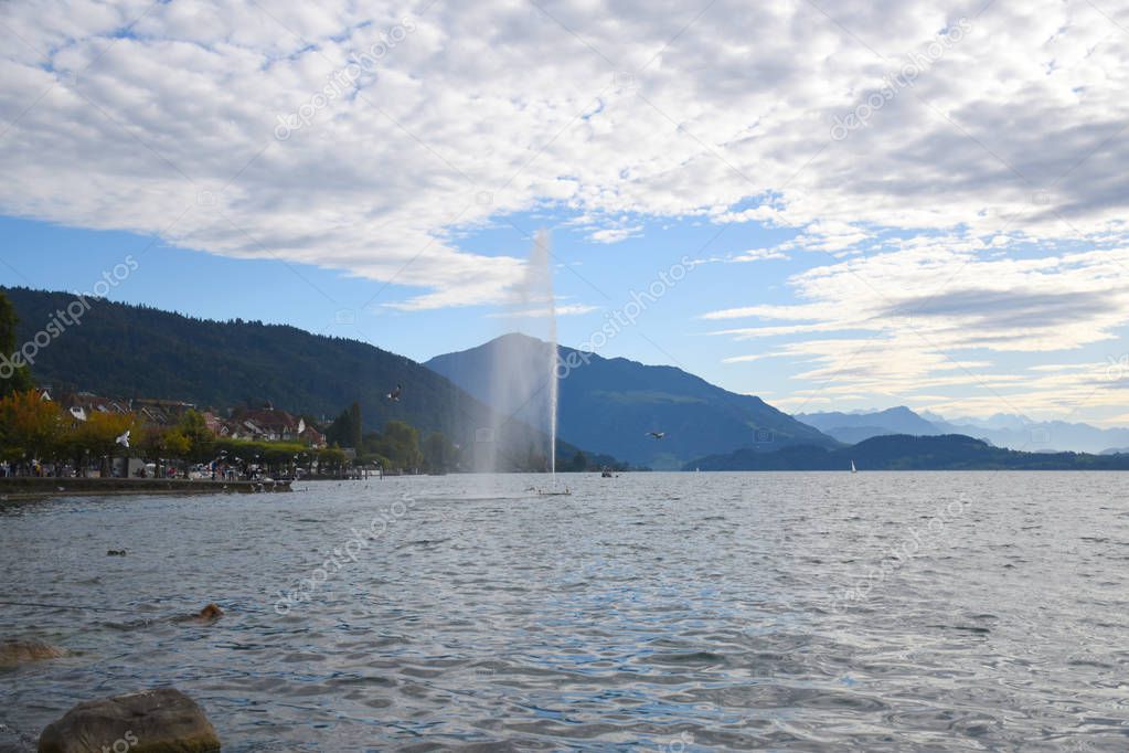 Landscape view of Lake Zug with fountain in lake and Mount Rigi on background 