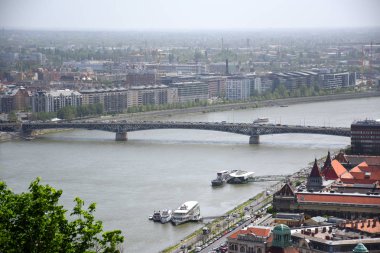 Panoramik, Lagymanyos mahallesinin siluet manzarası, arkada Petofi Köprüsü ile gemiler Tuna Nehri 'nde yüzerken