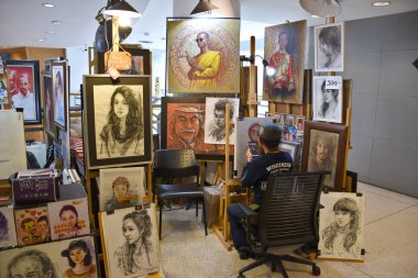 Bangkok, Tayland 08.23.2019: Bir Taylandlı sanatçı Bangkok Sanat ve Kültür Merkezi veya Bacc 'taki cep telefonu fotoğrafına dayanan beyaz bir tuval üzerinde renkli kalemlerle gerçekçi bir portre çiziyor
