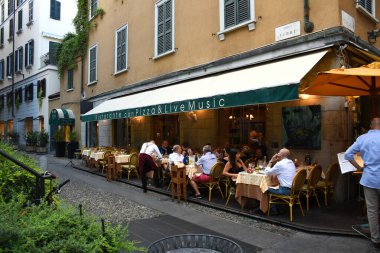 Milan, İtalya, 08.04.2019: Brera 'nın güzel, sevimli, romantik sokaklarında iyi yemek ve şarapları olan geleneksel İtalyan restoranları. Turistler, yerel halk orada aperatif ya da akşam yemeği yiyor.