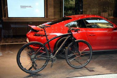 Milan, İtalya - 07.06.2019: Porsche Design Italia mağazası vitrini ve Porsche süperarabası ve Porsche bisikletiyle Via della Spiga 'ya giriş