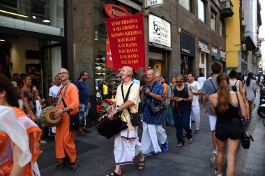 Milan, İtalya - 06.07.2019: Ruhani, dini ve mutlu Krishna inananlar Torino alışveriş caddesinde güneşli bir günde dans ediyor, şarkı söylüyor ve geçit töreni yapıyorlar, Via Torino, Milano 'da