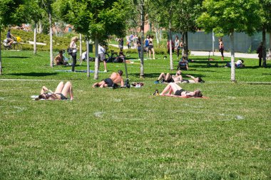 Milan, İtalya 06.20.2020: Milano 'daki yeni Ağaç Kütüphanesi parkının çimlerine boyanmış ve güneşten keyif alan insanlar