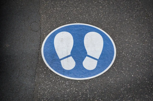 安全な社会的距離青と白の足マークはここを歩くと距離を保つために床に隔離されています — ストック写真