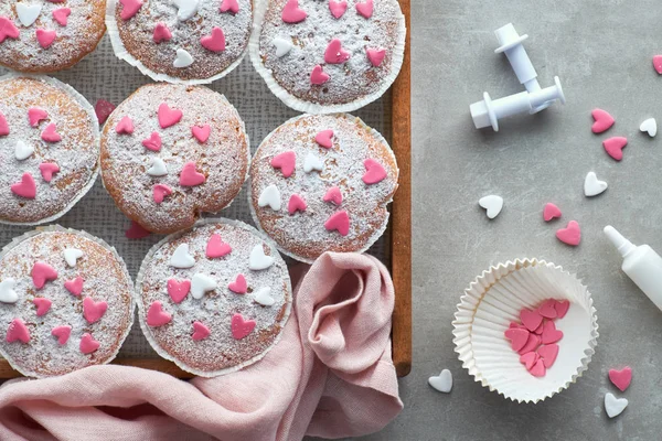 Muffins saupoudrés de sucre avec des coeurs de glaçage fondant rose et blanc — Photo