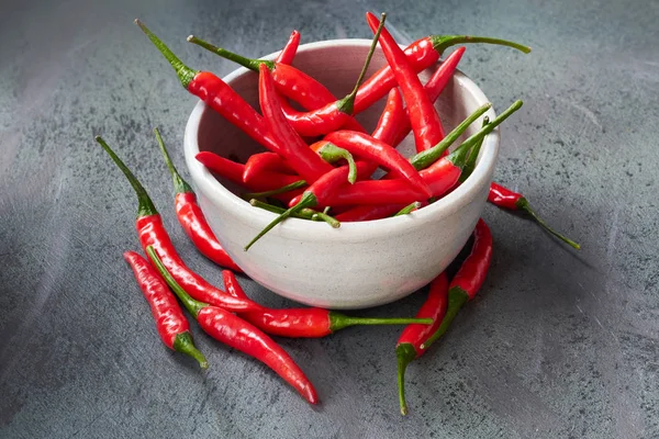 Překlošený na červených chilli papriček v keramickém míse nad temnotou textu — Stock fotografie
