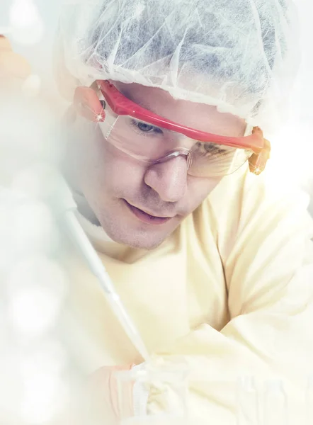 Young male scientist with automatic pipette, tinted
