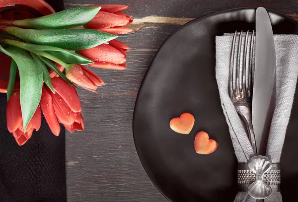 Zwarte borden, zwarte servetten, vintage bestek met rode tulpen en — Stockfoto