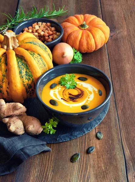 Spicy pumpkin soup with chili and garlic served in dark bowl