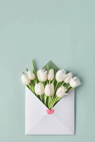 Tulipes blanches dans une enveloppe en papier avec autocollant coeur décoratif sur — Photo