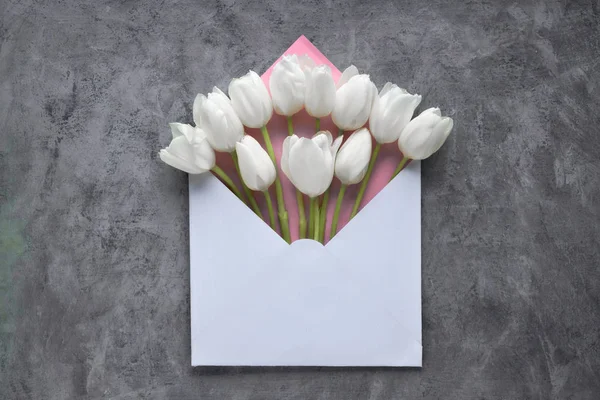 Primavera plana laica, tulipanes blancos en sobre en textura oscura — Foto de Stock