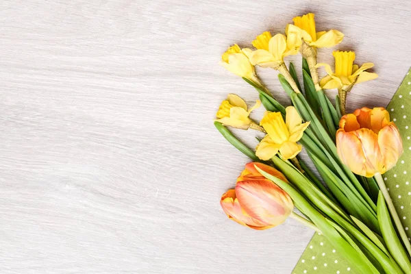 Bunch of tulips and narcissus on textile on wood, copyspace — Stock Photo, Image