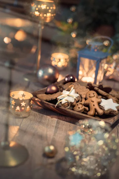 Vánoční cukroví na zdobeném stole se svíčkami — Stock fotografie