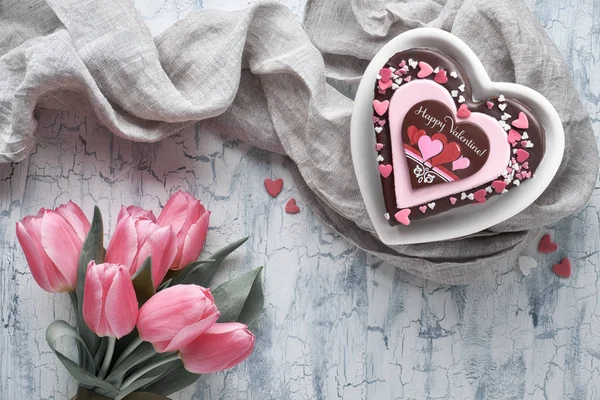 Valentine heart cake with text "Happy Valentine" and pink tulips — Stock Photo, Image