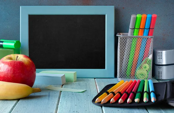 Kantoorbenodigdheden en fruit op een tafel voor blanco schoolbord — Stockfoto