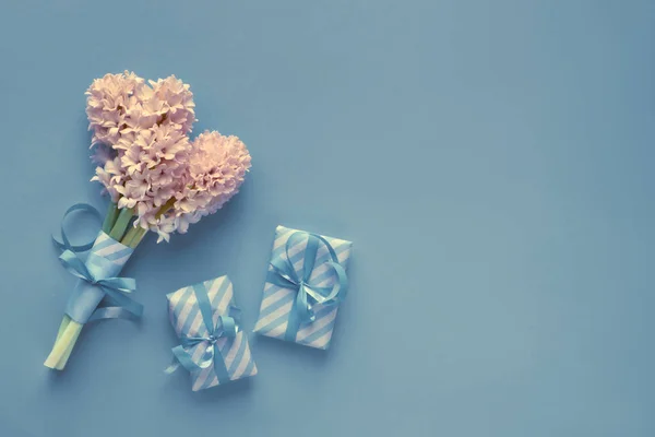 Blue paper background with tied bunch of pink hyacinth flowers — Stock Photo, Image