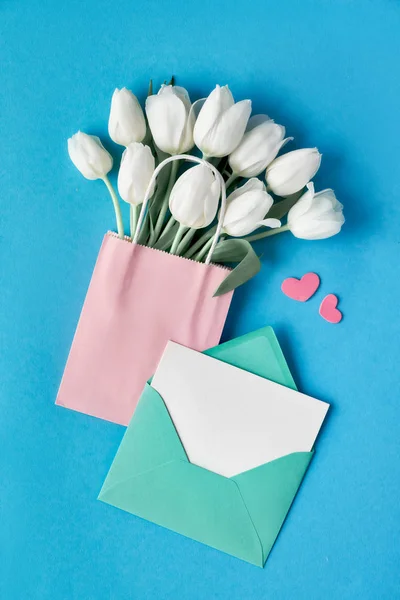 Springtime flat lay, white tulips in paper bag on blue mint back — ストック写真