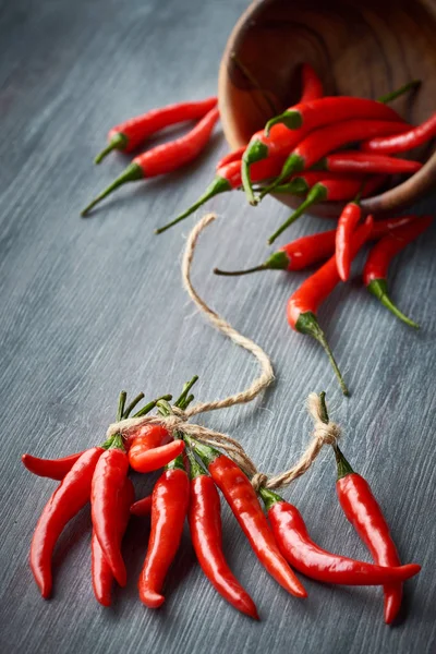 Close-up op rode hete chili pepers gebonden met een koord op donker hout — Stockfoto