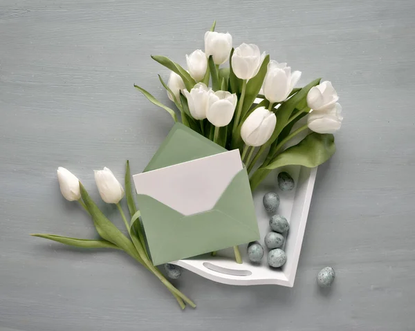 Tarjeta en blanco en sobre de papel con el ramo de tulipanes blancos en un — Foto de Stock