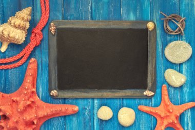 Deniz kabukları, halat ve mavi kukularında yıldız balığı olan boş bir karatahta.