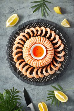 Limon ve sarımsaklı karides, limonlu, koyu bir tabakta servis edilir.