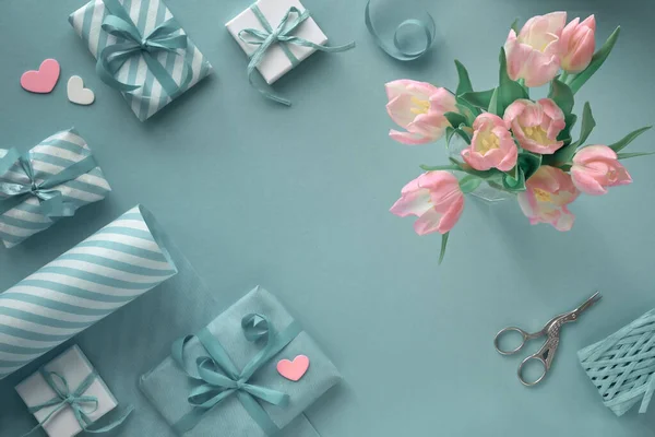 蓝色背景，粉色郁金香，条纹包装纸和礼物 — 图库照片