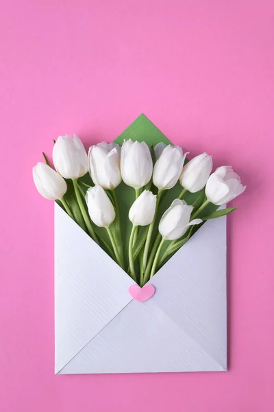 Tulipanes blancos en sobre blanco y verde sobre fondo de papel rosa — Foto de Stock