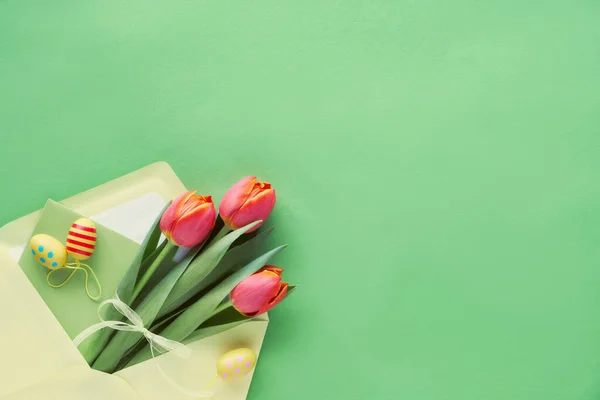 Easter flat lay on green paper. Bunch of orange tulips in paper — Stock Photo, Image