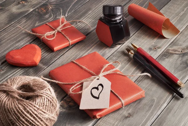 Verpakt cadeautjes, papier, snoer en etiketten op bruine houten tafel — Stockfoto