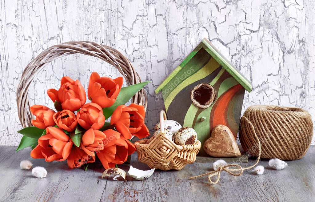 Easter arrangement with wooden wreath, red tulips and birdhouse