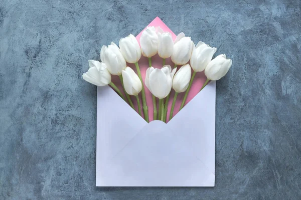 Pose plate printanière, tulipes blanches dans une enveloppe blanche et rose sur — Photo